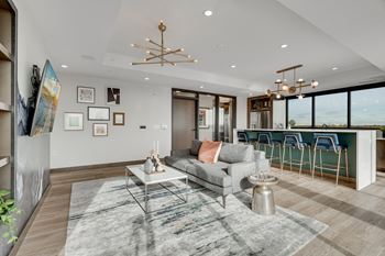 a living room with a gray couch and a bar with blue chairs